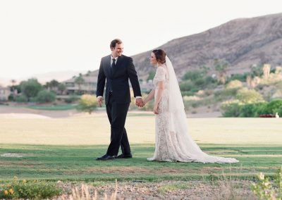 A man and woman holding hands on the grass.