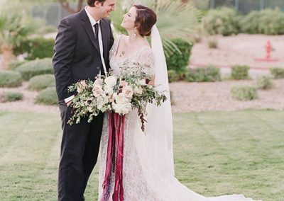 A man and woman standing in the grass holding hands.