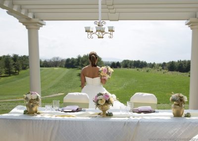 A bride standing at the table in front of her wedding dress.