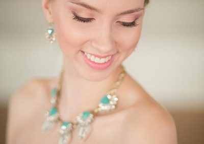 A woman wearing a necklace and earrings smiling.