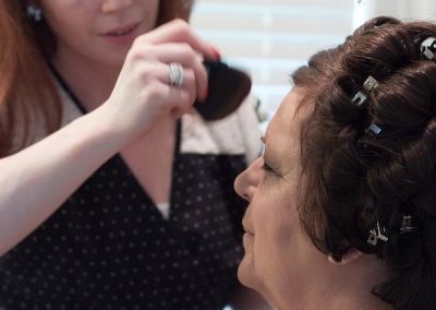 A woman is getting her hair done by another person.