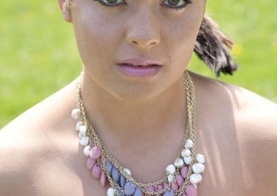 A woman wearing a necklace with pink and purple beads.