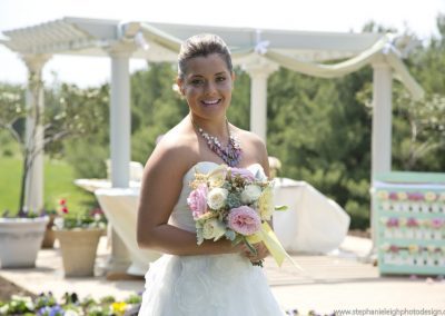 A woman in white dress holding flowers near a gazebo.