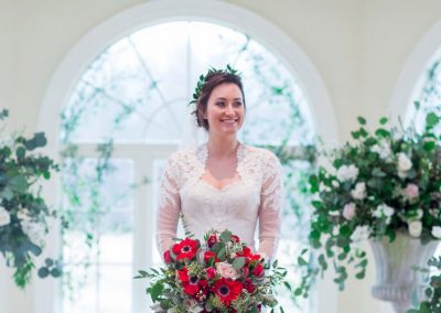 A woman holding a bouquet of flowers in front of a window.