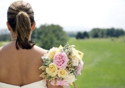 A bride with her bouquet in the grass.