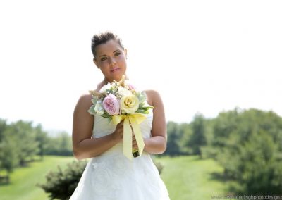 A woman in white dress holding flowers and posing for the camera.