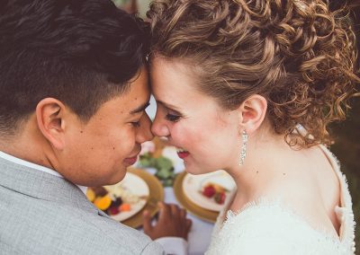 A man and woman kissing each other while holding food.