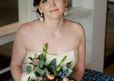 A woman sitting on top of a bench holding a bouquet.