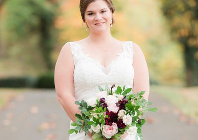 A bride holding her bouquet of flowers in front of the road.