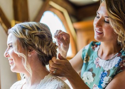 A woman is helping another woman with her hair.