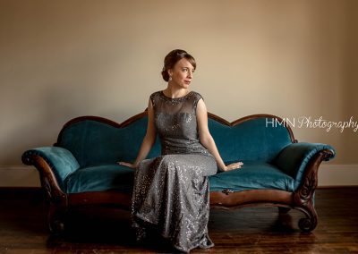 A woman in a dress sitting on top of a couch.