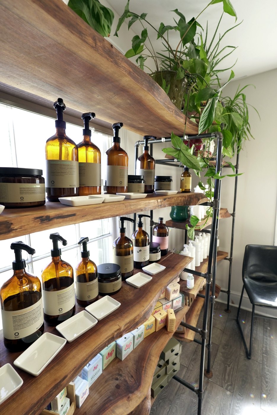 Live-edge wood shelf of amber refill bottles at the Enlightened Styles refillery in Warrenton, VA