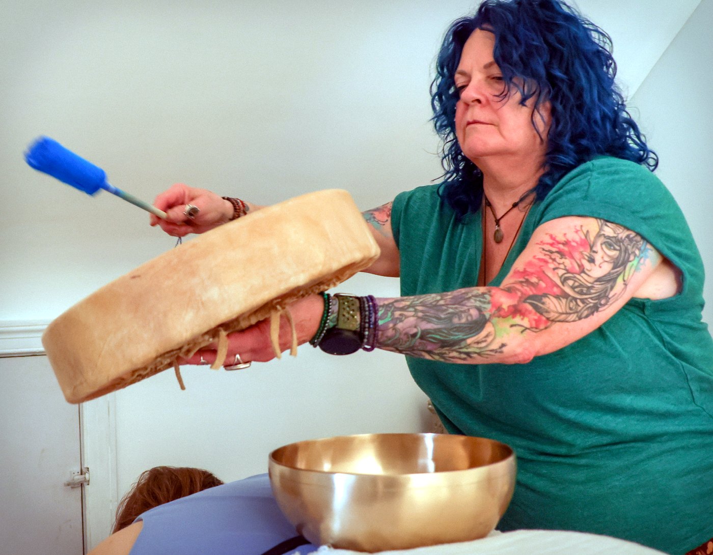 Practitioner playing a frame drum during a sound healing session at Enlightened Styles in Warrenton, VA